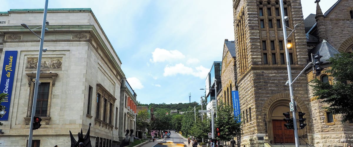 A street with a large stone building, a crosswalk, and a cyclist.