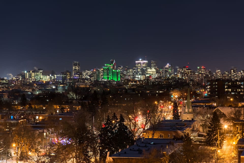 Une vue nocturne d’une ville, avec des bâtiments illuminés et un paysage enneigé.