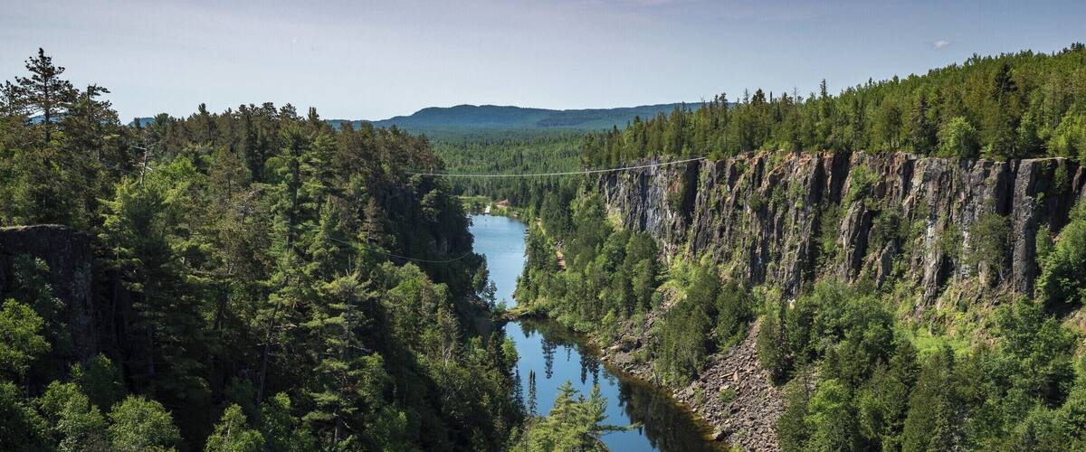 A river winding through a forested gorge with steep cliffs.