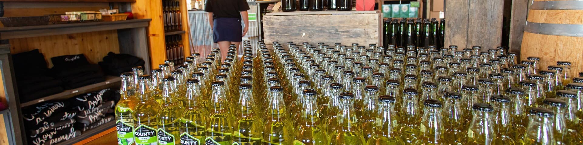 A wooden table filled with bottles of County Cider Lime.