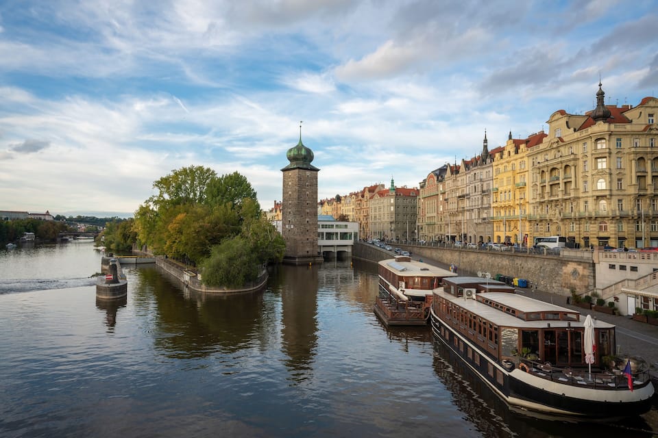 Un río con barcos, una torre y edificios históricos a lo largo de la orilla.