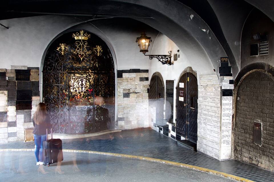 An arched corridor with a decorative gate, stone walls, and inscriptions.