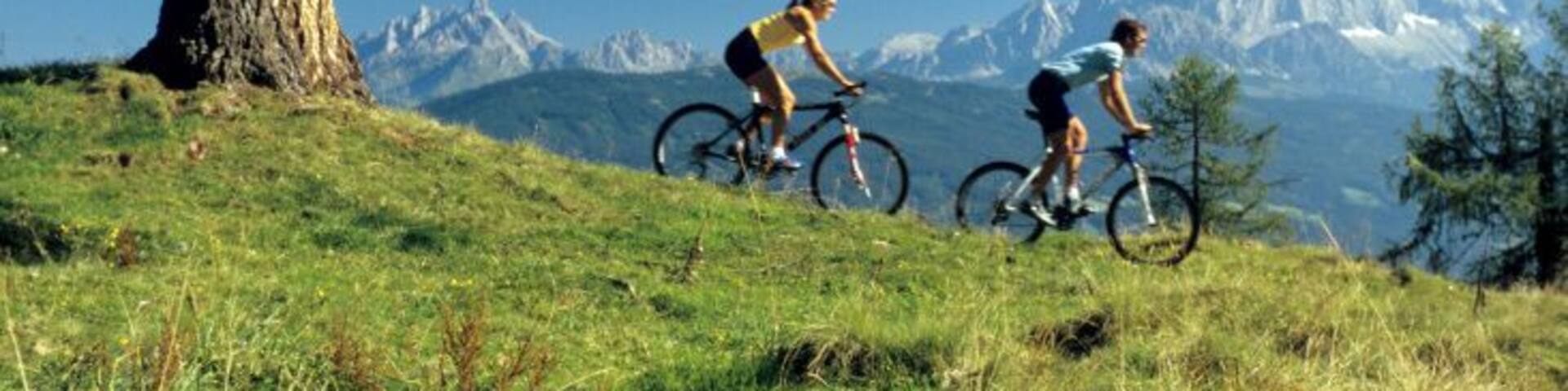 Austria, Salzburger Land, couple mountain biking, side view