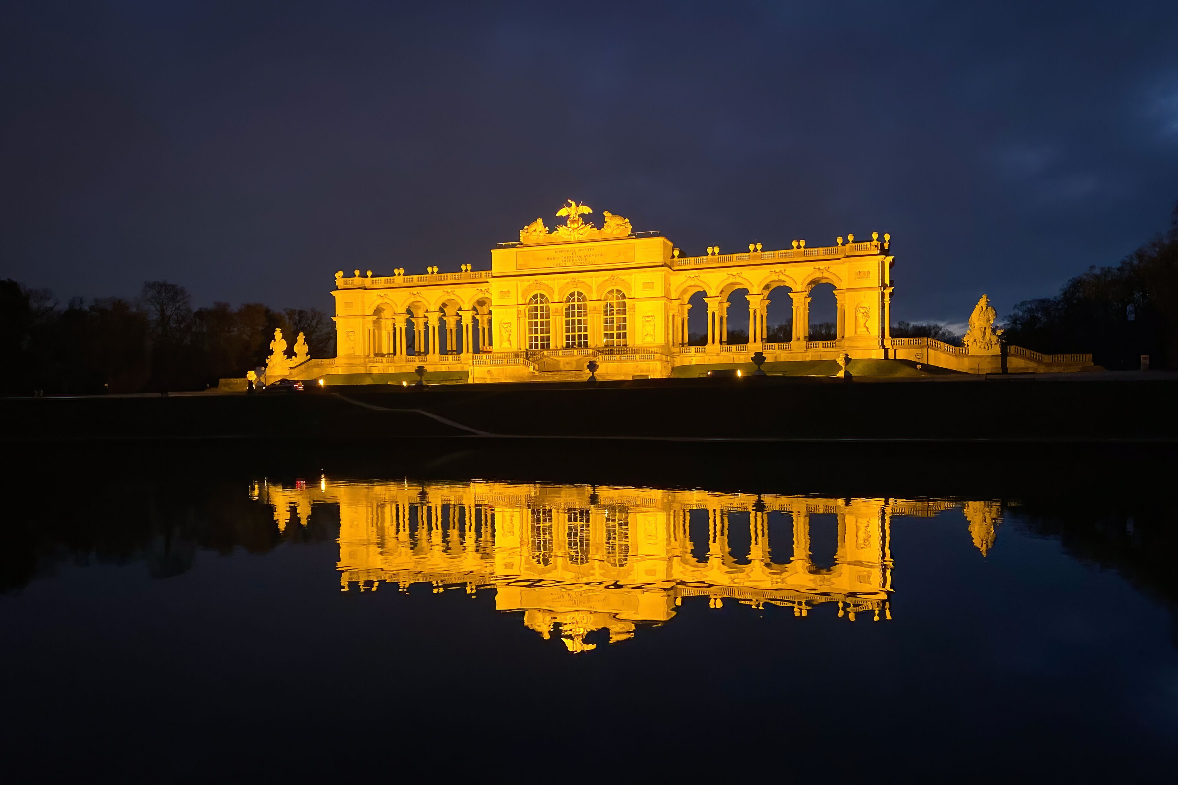 Vienna, Austria - January 20, 2020: The illuminated Glorietta at Schönbrunn Palace Park in winter at dusk against cloudy sky