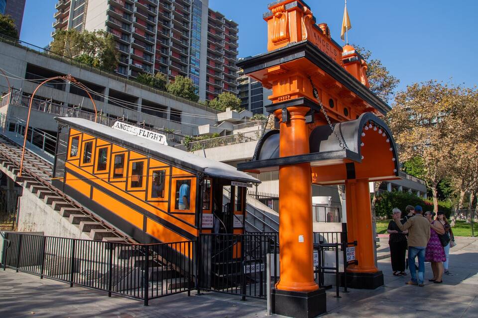 A vintage train station with an orange facade and a staircase leading up to it.