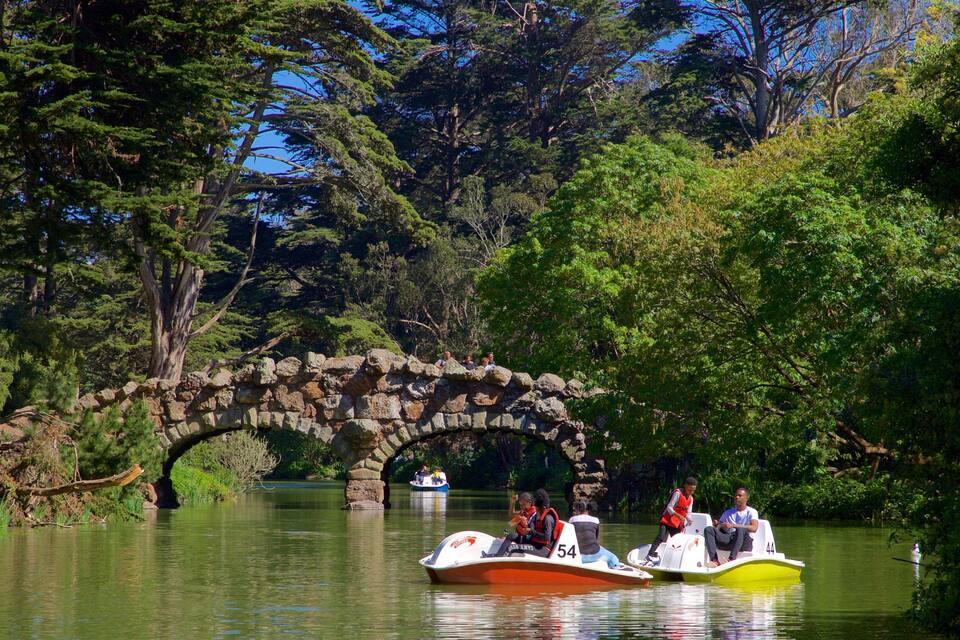 A stone bridge over a calm river surrounded by lush greenery and trees.
