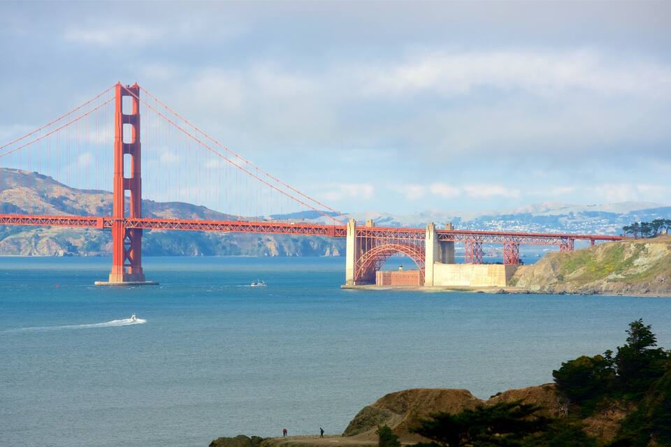 The Golden Gate Bridge spanning a body of water with hills in the background.