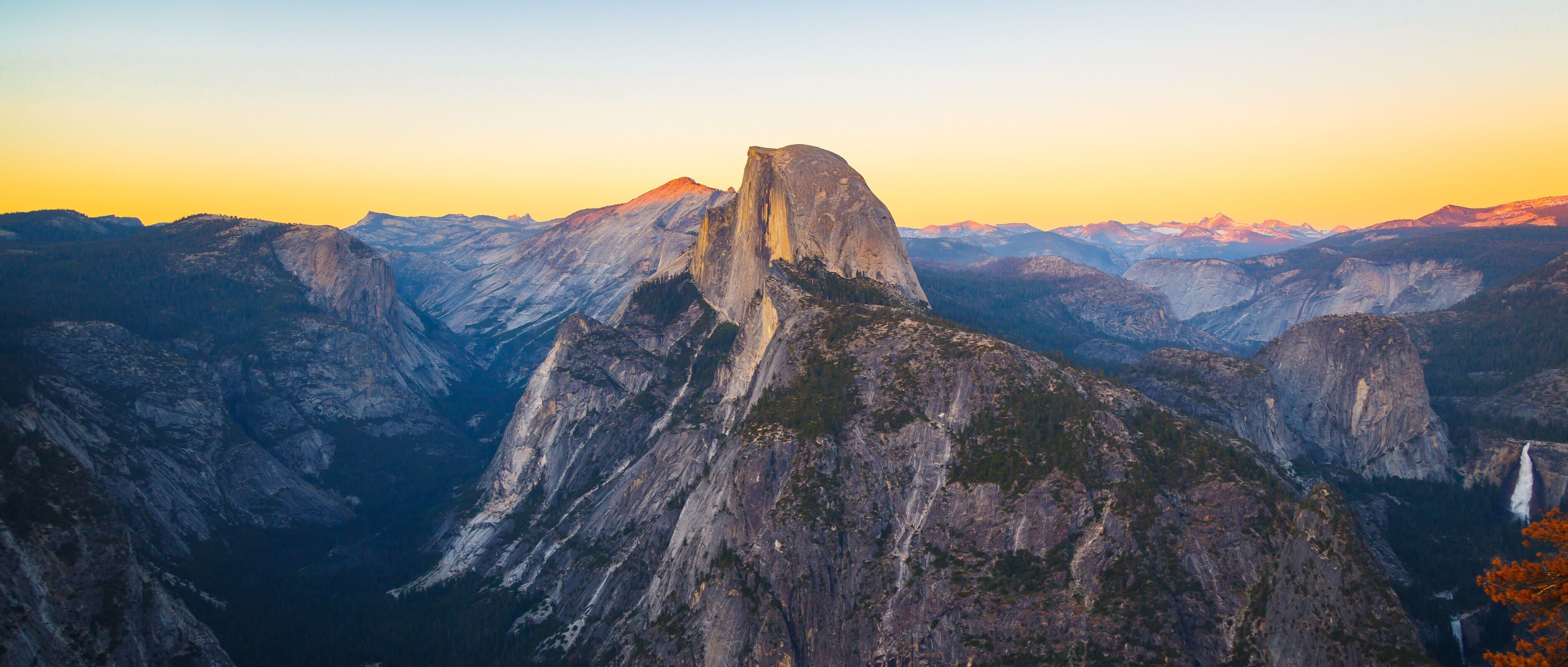 A mountain range with a prominent peak, likely a famous landmark, surrounded by rugged terrain and a clear sky.