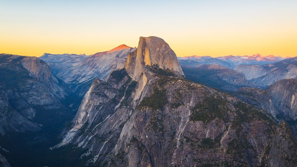 A mountain range with a prominent peak, likely a famous landmark, surrounded by rugged terrain and a clear sky.