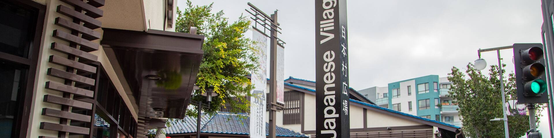 Una calle con la Plaza del Pueblo Japonés, un edificio con techo azul y una tienda llamada Tokyo Cosmetics.