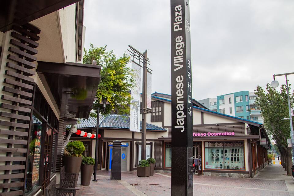 Une rue où se trouve le Japanese Village Plaza, un bâtiment avec un toit bleu, et un magasin appelé Tokyo Cosmetics.