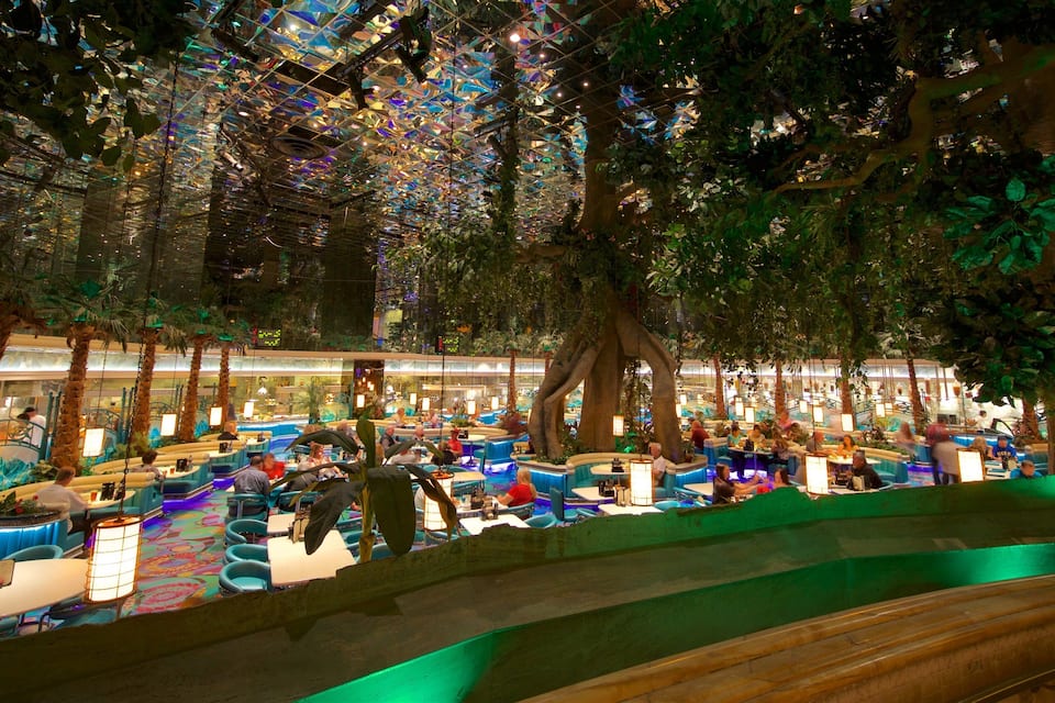 An indoor atrium with artificial trees, seating areas, and a glass ceiling.