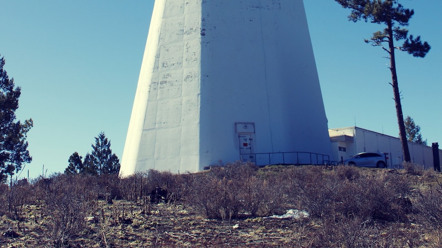 vertical-axis solar telescope in New Mexico, white building blue sky and green tree