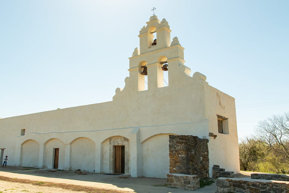 Une église blanche dotée d’un clocher et de portails en arc de cercle.