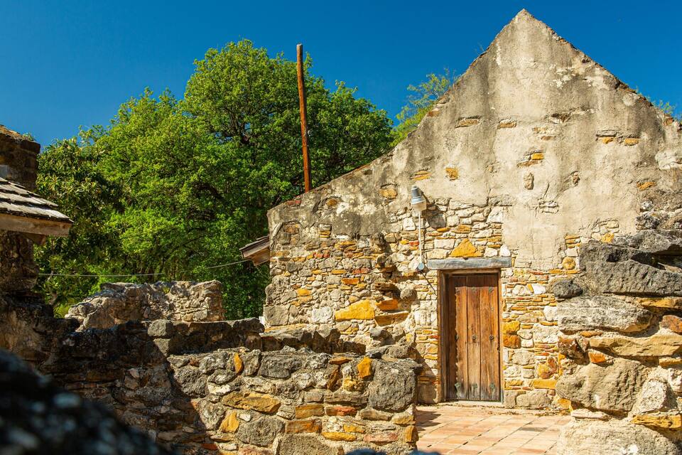 A stone building with a wooden door and a tiled roof.