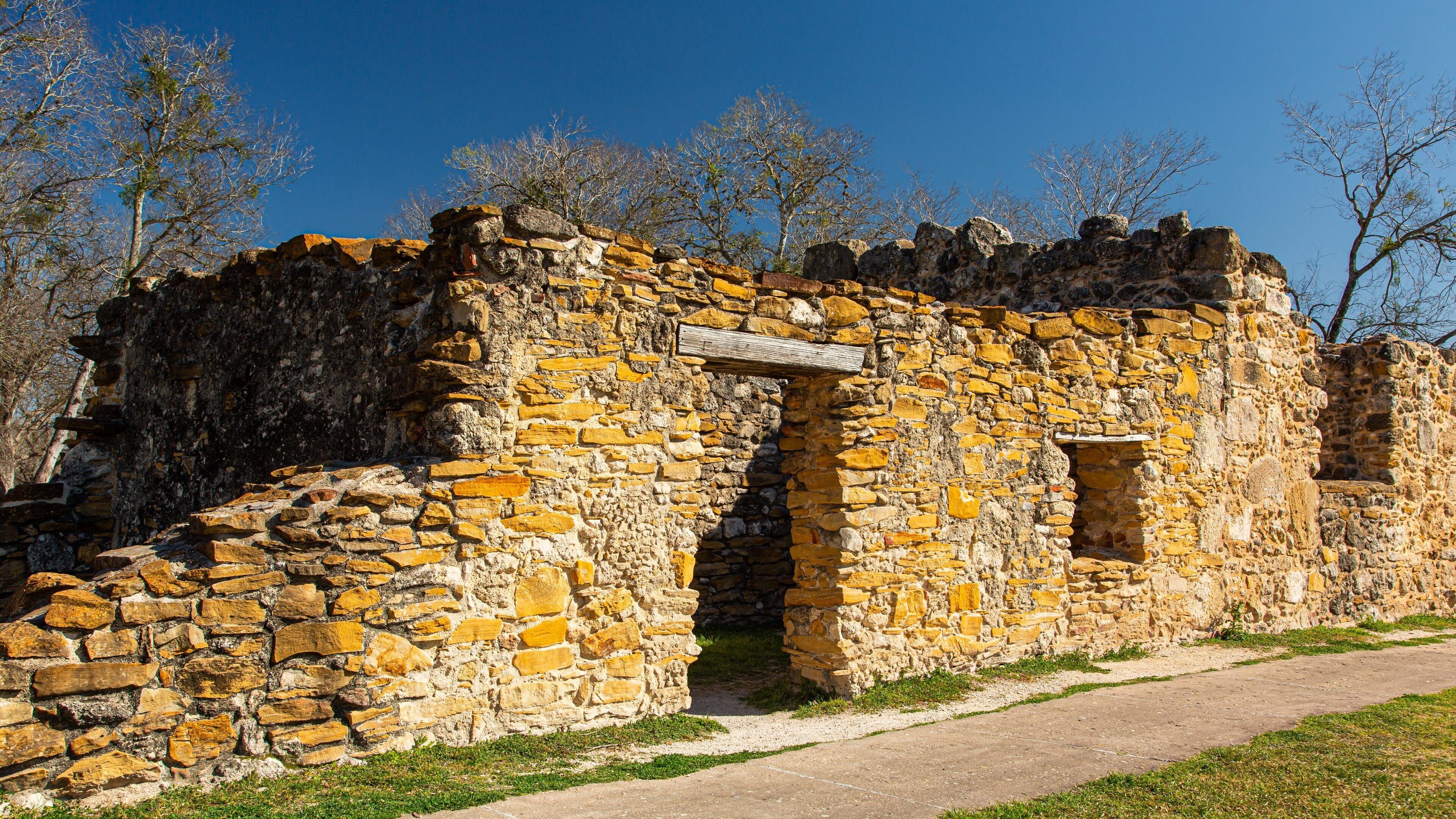 Une ruine de pierre avec une porte en arc de cercle et une enseigne en bois.