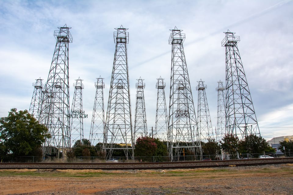 Une série de hauts pylônes métalliques transportant des lignes électriques, avec une voie ferrée au premier plan.