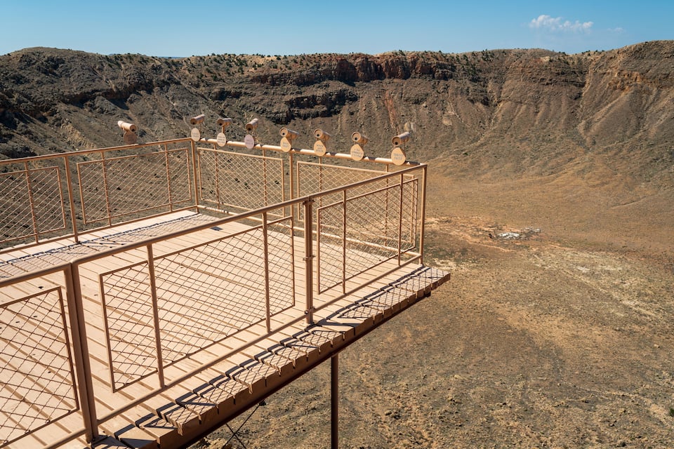 A metal observation platform overlooking a barren landscape with a steep cliff.