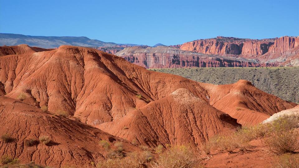 A red desert landscape with layered hills and distant mountains.