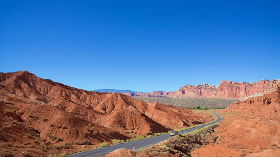 A winding road through a red desert landscape with distant mountain ranges.