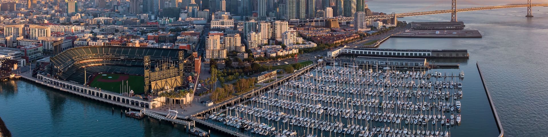 San Francisco skyline, Oracle Park, and a bustling marina at sunrise. Aerial view of the city's iconic landmarks. South Beach Harbor, San Francisco, California, USA