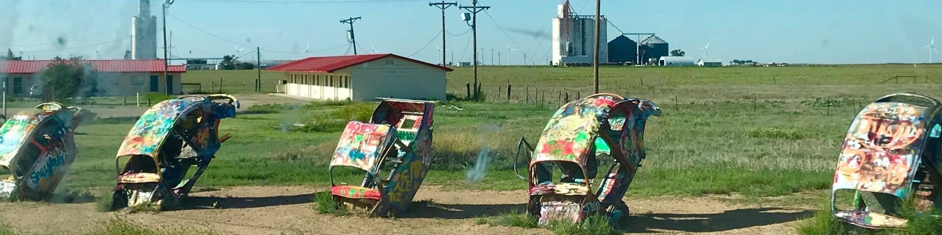 lug Bug Ranch -- also known as Bug Ranch, Bug Farm, and Buggy Farm -- was created in 2002. The five wrecked Volkswagen Beetles, buried hood-down in the ground, were the idea of the Crutchfield family, who owned the Longhorn Trading Post and Rattlesnake Ranch next door.
Slug Bug Ranch.
It began when a huge corporate Travel Plaza was built on the opposite side of the Crutchfields interstate exit. They figured they could stay in business if they could siphon away traffic with something eye-catching and engaging. Slug Bug Ranch seemed a natural choice: a parody of the popular Cadillac Ranch, 35 miles west. At the time, the Beetle wrecks were painted a pristine bright yellow, and a sign next to them encouraged, "Sign a Bug."
Slug Bug Ranch.
The Crutchfield's were right about one thing: Slug Bug Ranch has proved popular as an attraction. Unfortunately, it flopped as a business plan, and the Trading Post closed only a year after it was built. Its advanced state of decay is a testament to the vigorous love it has endured from Route 66 travelers, who have felt free to modify the abandoned artwork with spray paint and whatever crowbars, hammers, blowtorches, etc. they apparently carry in their vehicles.