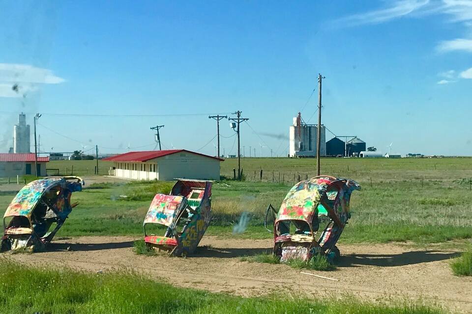 Quatro veículos tombados com grafites coloridos em um ambiente rural.