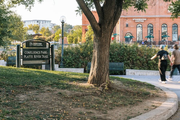 Parkschild für den Confluence Park – Platte River Trail, mit einem Baum und Bänken im Vordergrund.