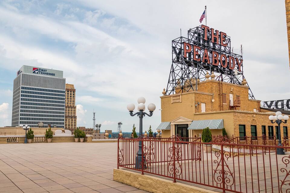 Una plaza de la ciudad con un edificio del Banco First Tennessee, un teatro con el cartel "THE PEABODY" y un área cercada con macetas.
