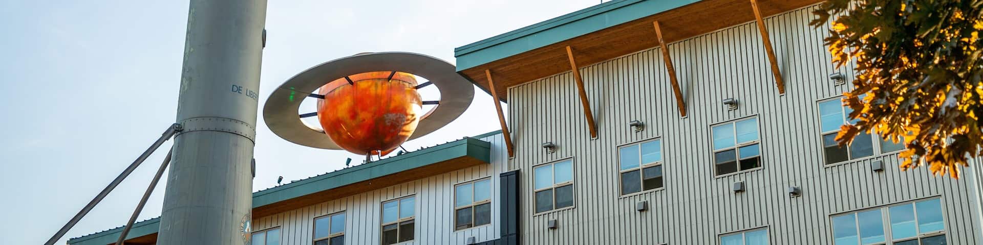 A rocket with a star emblem, a large spherical structure, and a building with vertical siding and windows.