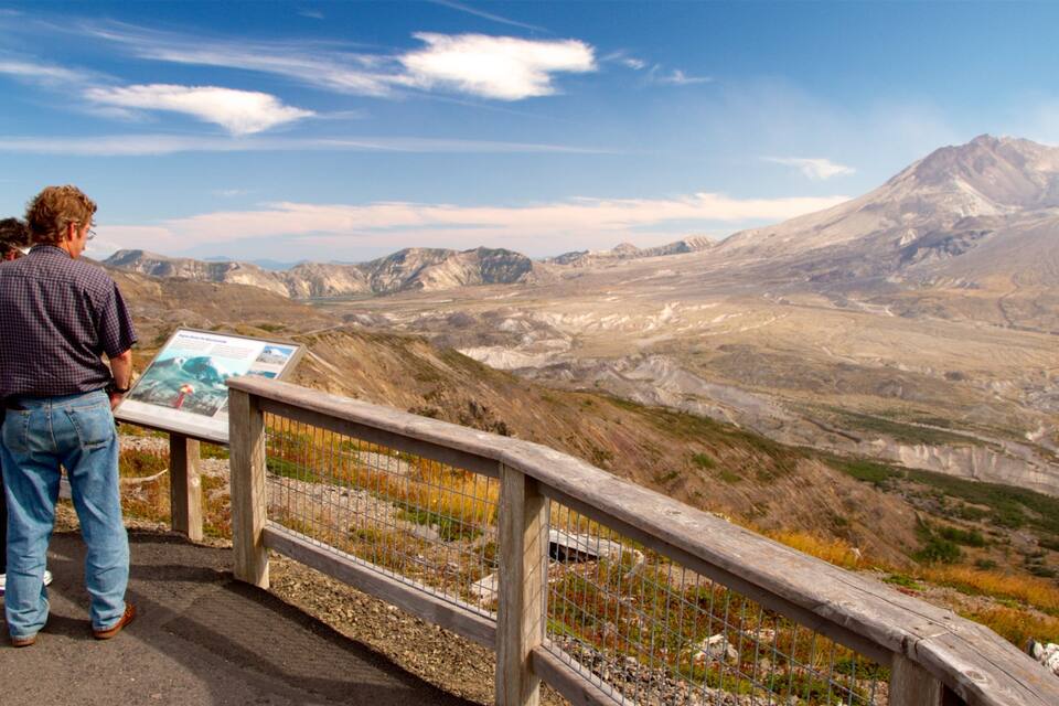 A mountainous landscape with a wooden viewing platform and a sign.