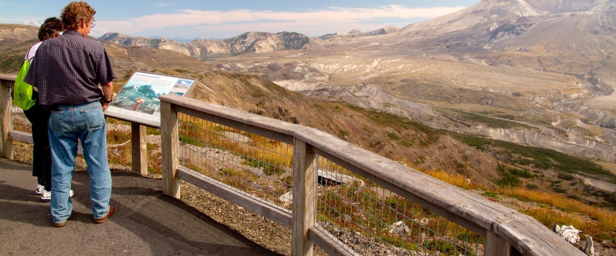 A mountainous landscape with a wooden viewing platform and a sign.