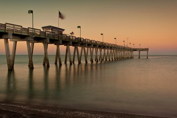 A pier extending into calm waters at sunset.