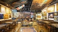 A café with tables and chairs, a bookshelf, and various paintings on the walls.