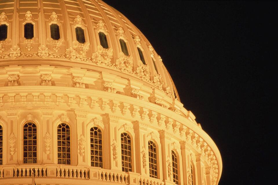 A grand, illuminated dome with intricate carvings and arched windows.