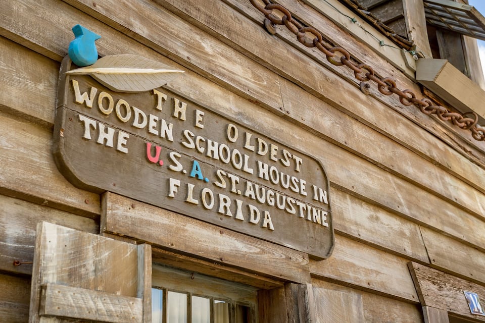 A wooden sign with the text "The Oldest Wooden Schoolhouse in the U.S.A. St. Augustine Florida".