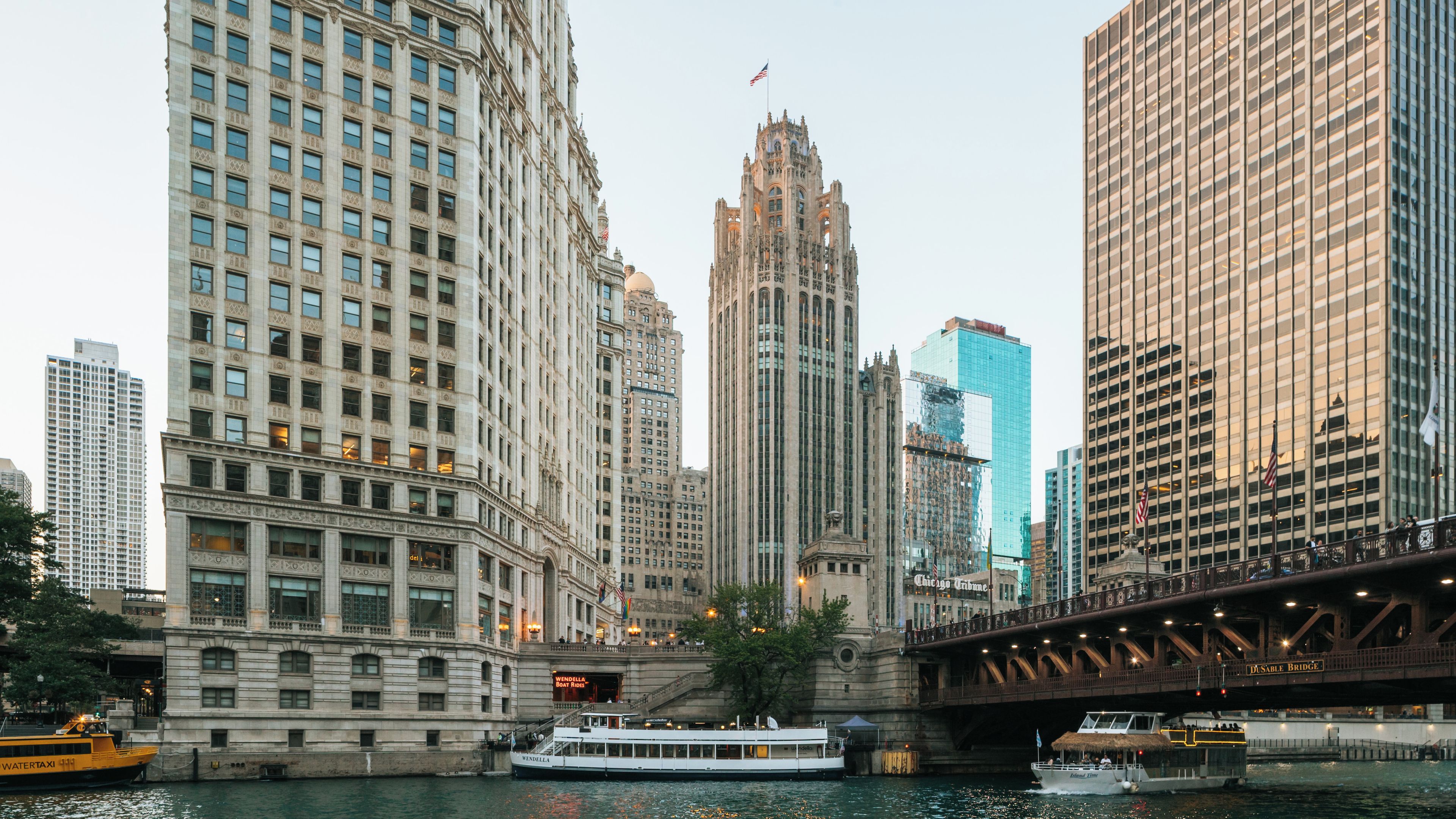 A river with boats, a bridge, and tall buildings.