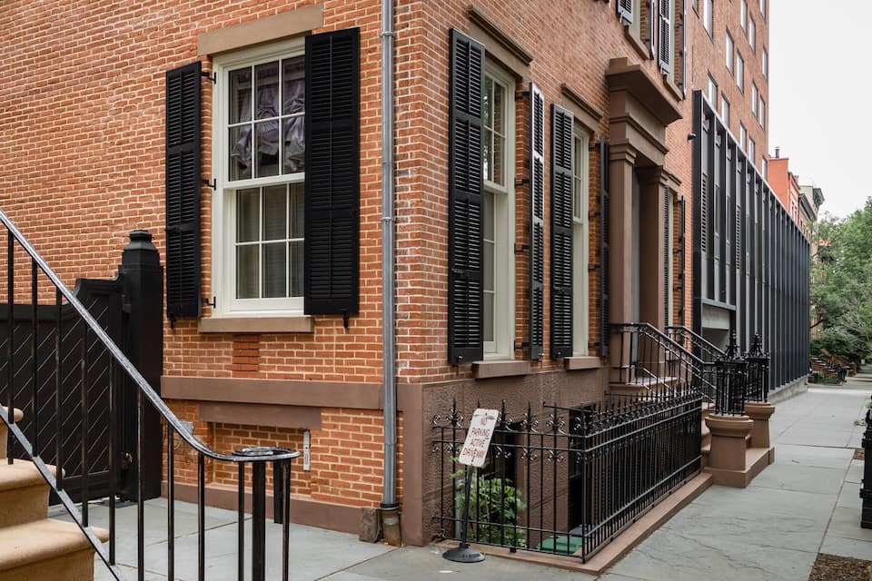 A brick building with black shutters and a staircase.