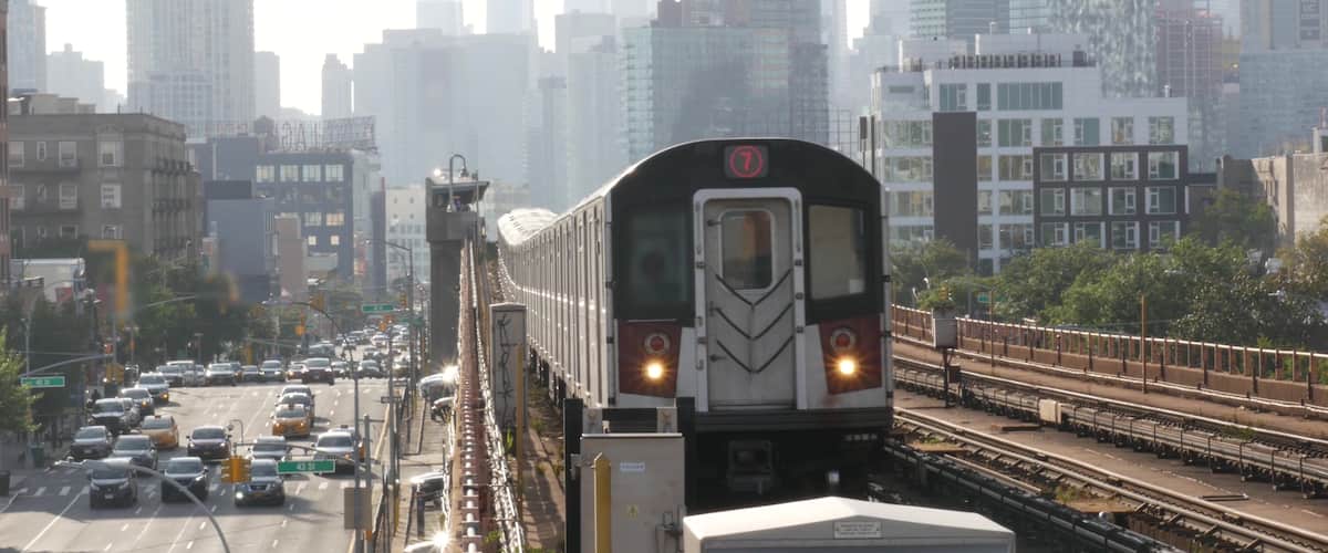 A train on tracks with a city skyline in the background.