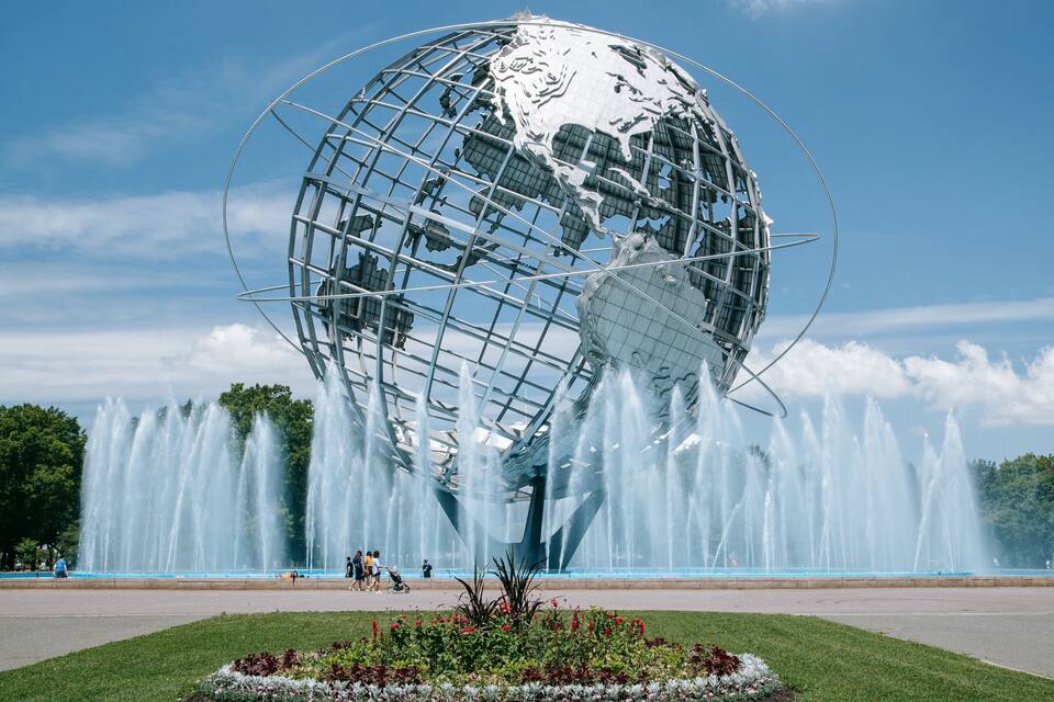 A large metallic globe sculpture surrounded by a water fountain display.
