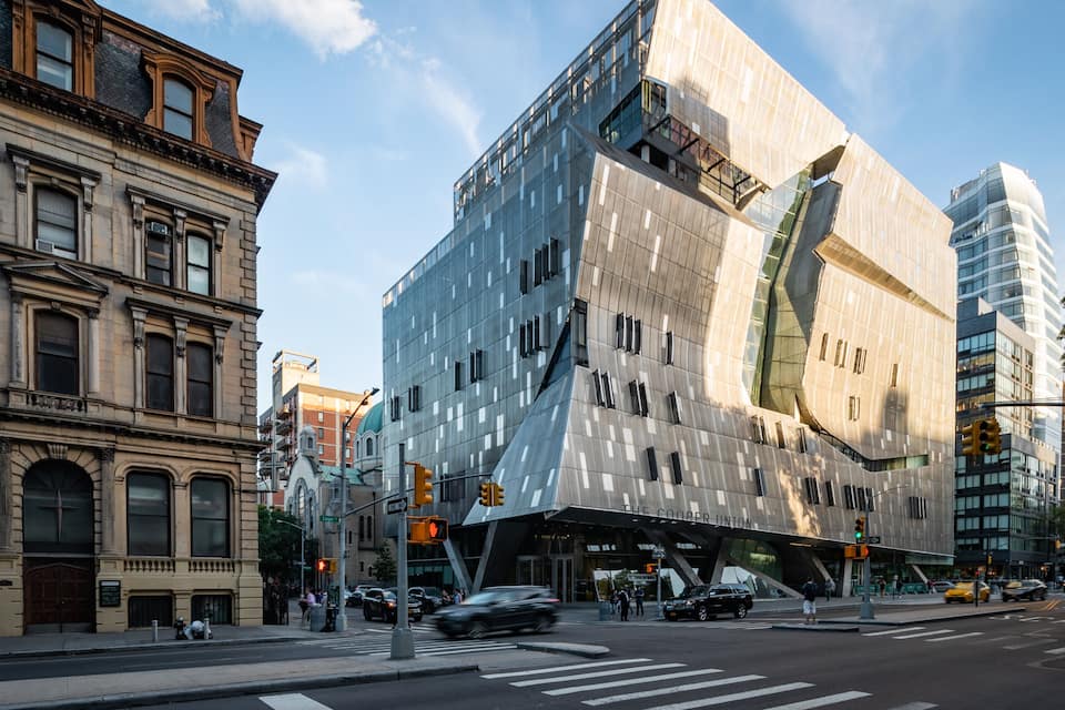 A modern building with a unique design, surrounded by older architecture.