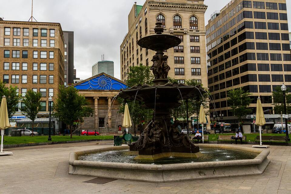 Una plaza pública con una fuente central, rodeada de edificios históricos y arquitectura moderna.