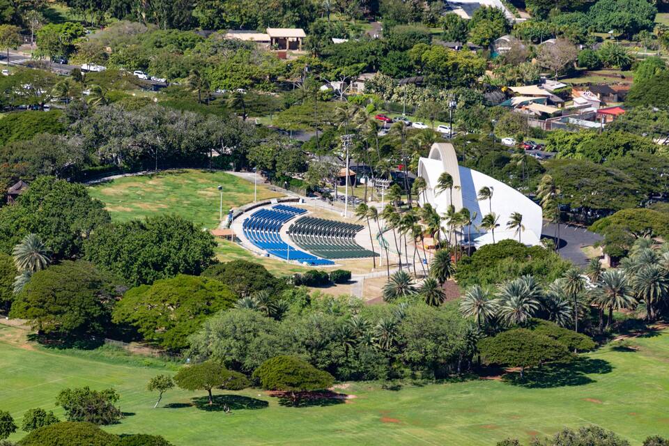 An aerial view of a stadium surrounded by lush greenery and palm trees.