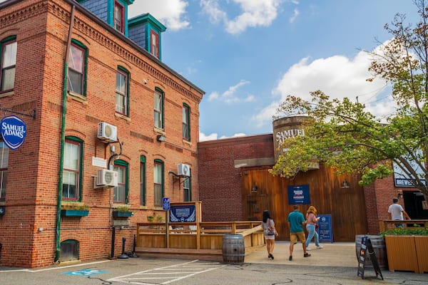 A red brick building with green window frames and a blue sign that reads "Samuel Adams."