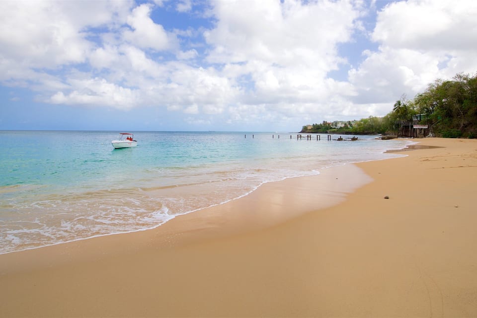 A beach with clear turquoise water, a boat, and a pier.