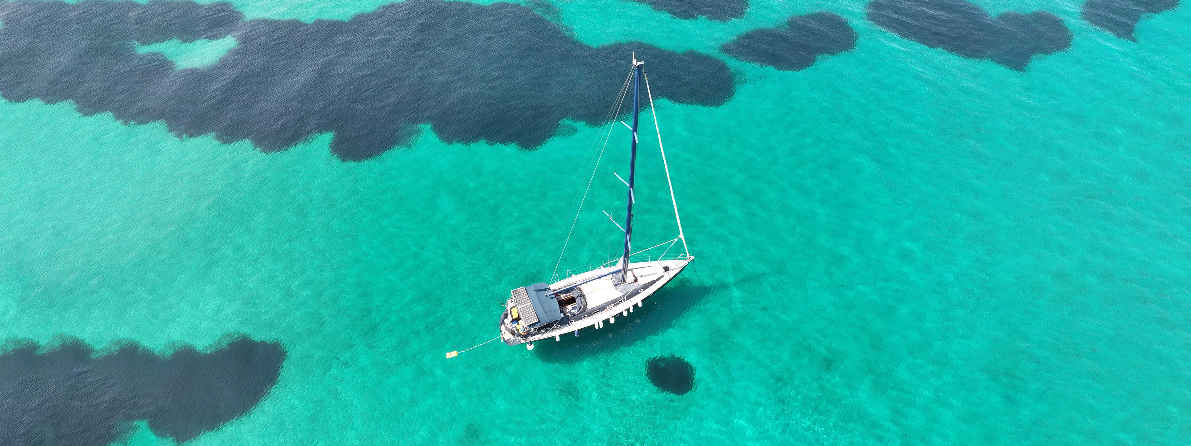 Aerial drone ultra wide panoramic photo of beautiful sail boat with white sails anchored in tropical exotic bay with emerald clear sea