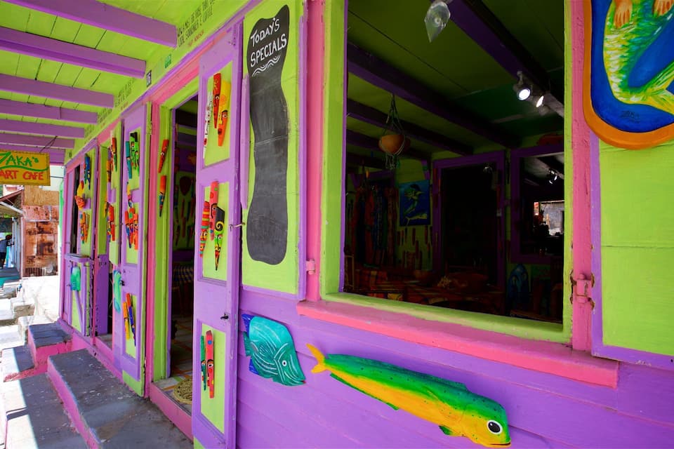 Un bâtiment aux couleurs vives, avec des portes et des fenêtres colorées, une enseigne indiquant les « plats du jour » et une fresque représentant des poissons sur le mur.