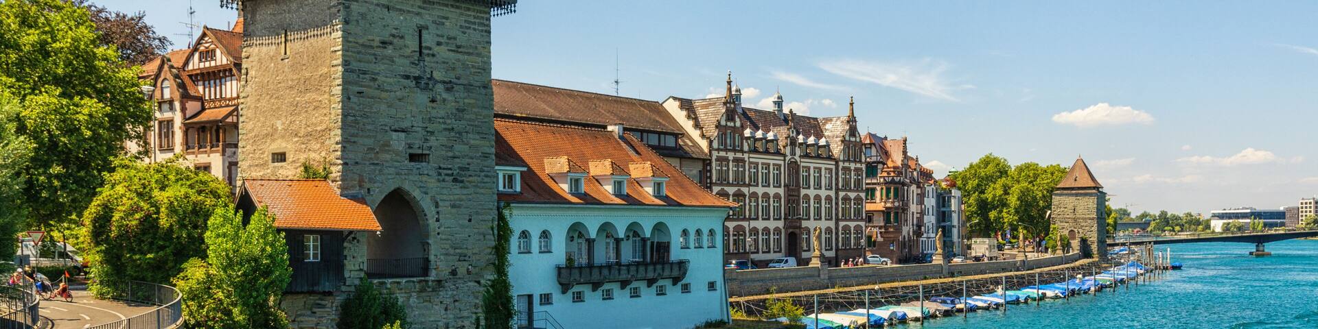 A historic tower, a river, and traditional buildings along a waterfront.