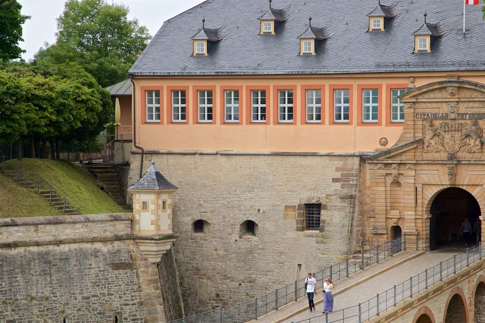 A historic building with a stone facade, a large arched entrance, and a staircase leading up to it.