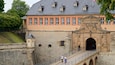A historic building with a stone facade, a large arched entrance, and a staircase leading up to it.